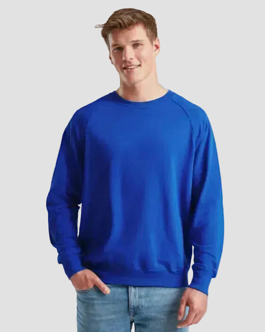 A man wearing a bright royal blue crewneck sweatshirt and light blue jeans, standing against a plain white background.