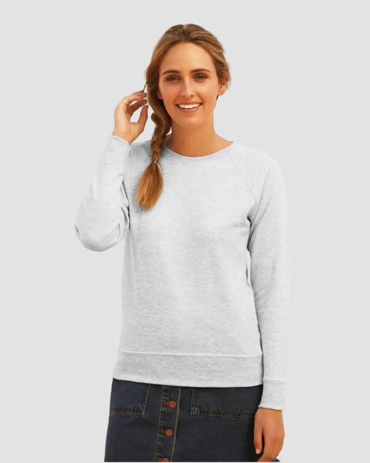 A woman wearing a light gray long-sleeve crewneck sweatshirt and a dark denim button-front mini skirt, standing outdoors with a blurred background.