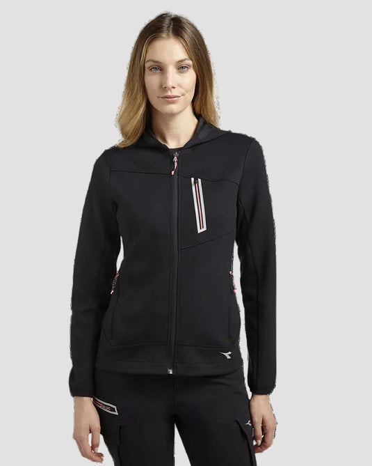 A woman modeling a black hooded zip-up jacket with a vertical chest pocket featuring white and red stripes, paired with black cargo pants, against a solid light gray background.