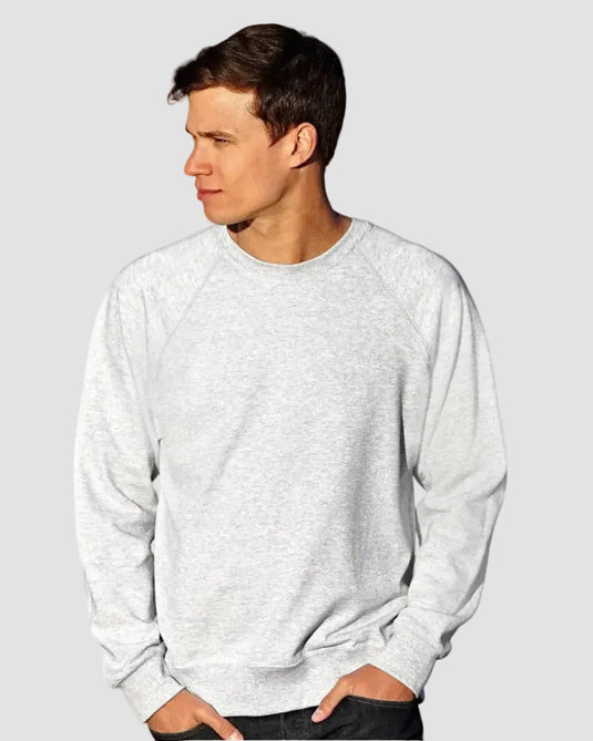 A man wearing a light gray heather crewneck sweatshirt, standing outdoors with a blurred natural background.